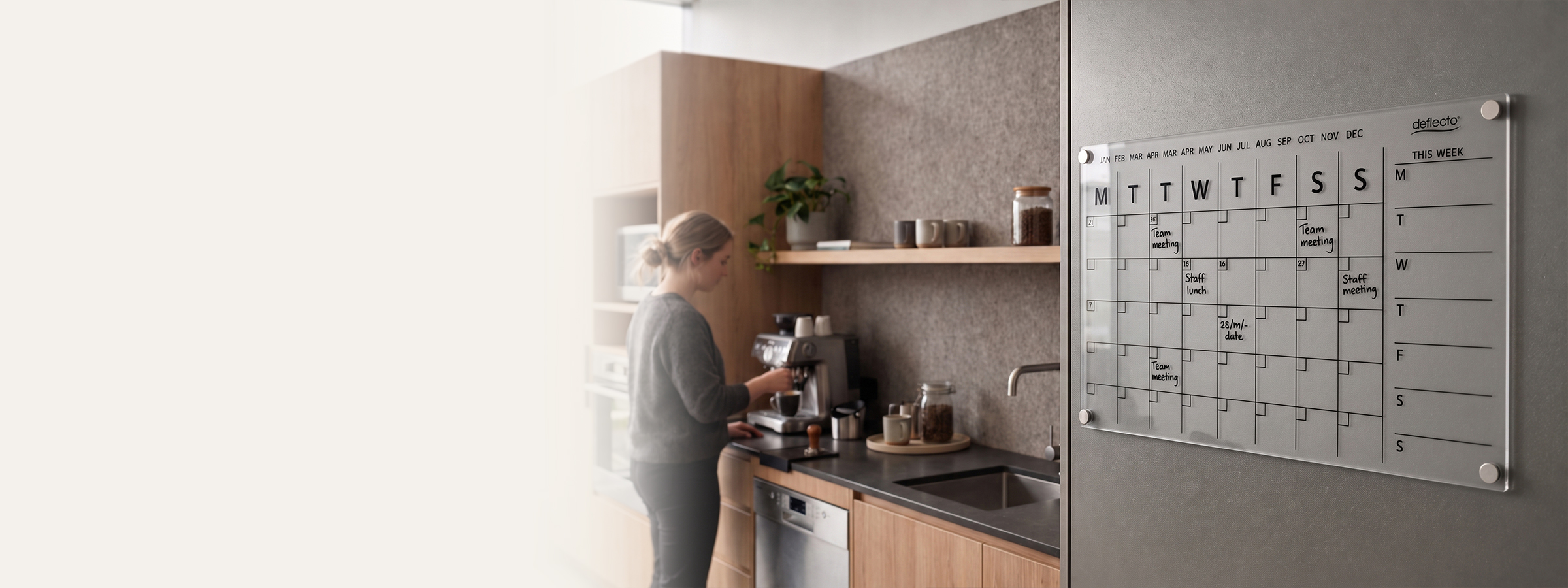 A clear acrylic magnetic wall planner mounted on a steel surface in a shared workplace.